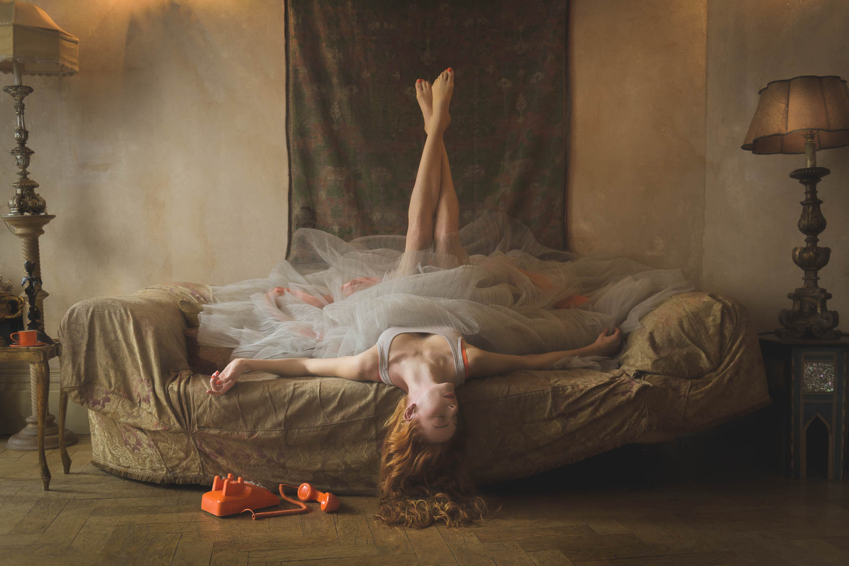 Red hair model lying on a couch with orange telephone on the floor photographed by Marc Rogoff (Fashion Image for Fragrance Brand Romilly Wilde)