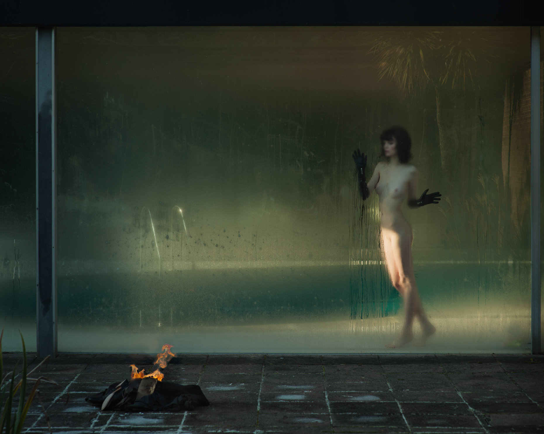 Dark haired model naked behind steamed glass window in a swimming pool photographed by Marc Rogoff (Bambi Magazine)